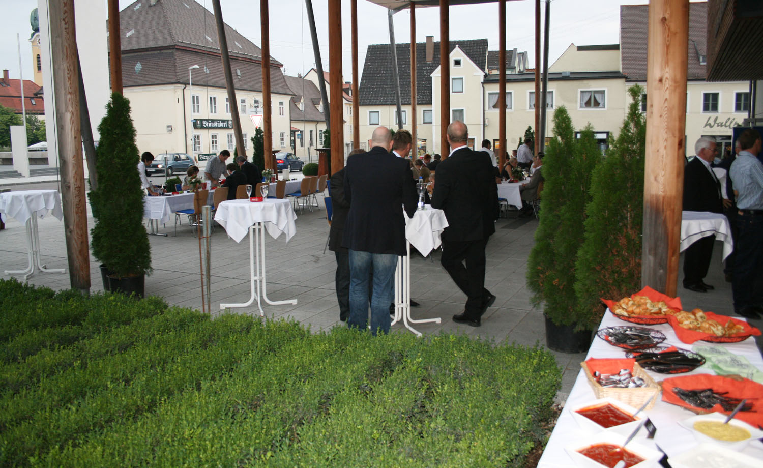 Die Menschen haben Steh-Tische auf den Vorplatz gestellt. 