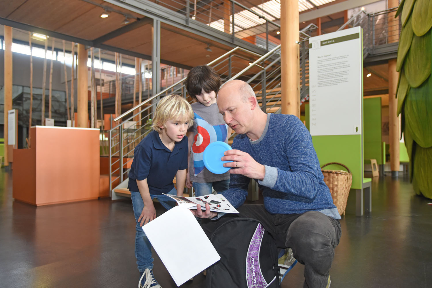 Ein Museumsmitarbeiter erklärt zwei Jungen den Inhalt des Hopfenzupferrucksacks